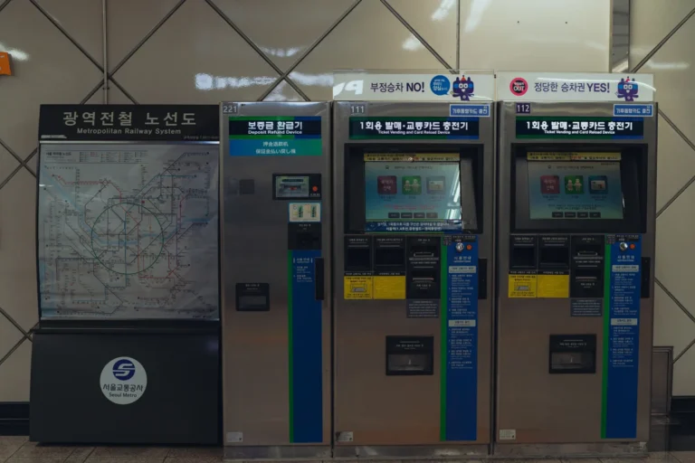 Ticket vending and transit card reload machines beside a Seoul metropolitan railway map