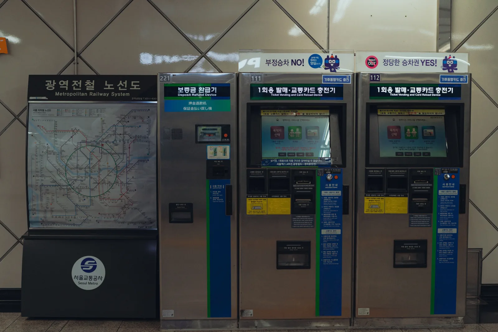 Ticket vending and transit card reload machines beside a Seoul metropolitan railway map