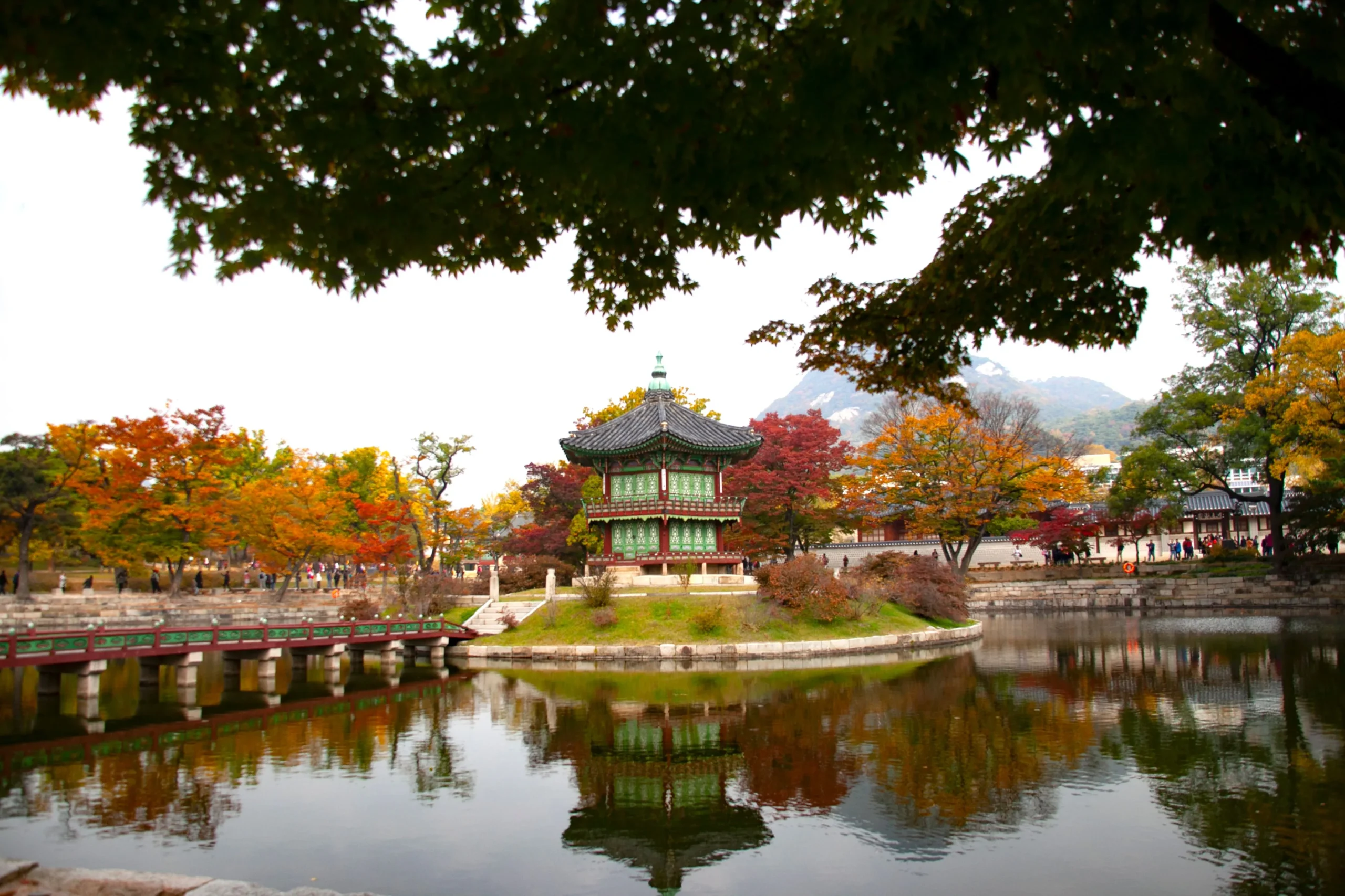 Hyangwonjeong Pavilion reflected in its pond among red, orange, and yellow autumn trees at Gyeongbokgung Palace