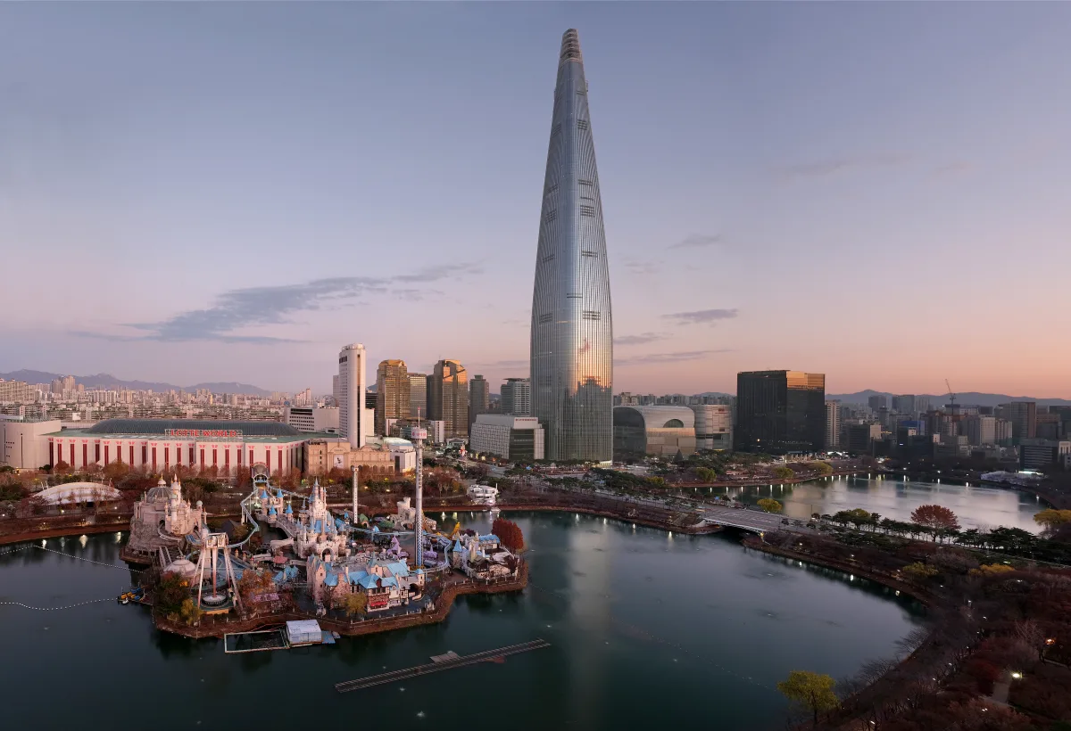 Lotte World Magic Island and Lotte World Tower beside Seokchon Lake at sunset