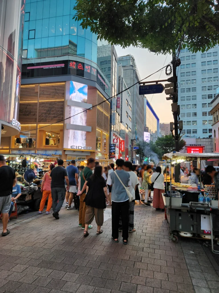 Shoppers walking between stores and food stalls on Myeongdong 7-gil