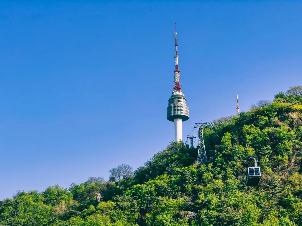 Namsan Seoul Tower and a cable car above a green hillside