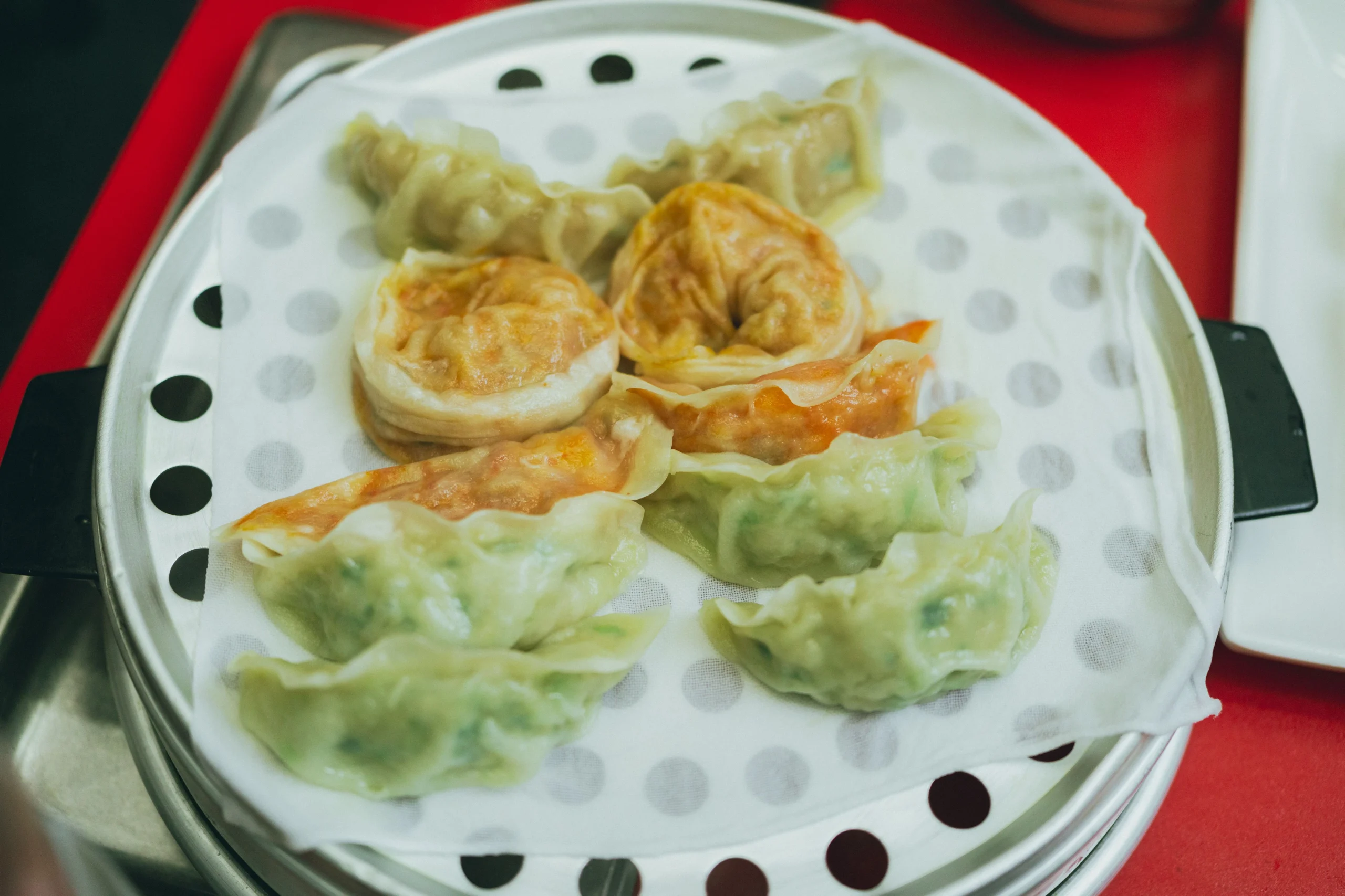 Assorted steamed and pan-fried Korean dumplings on a round tray