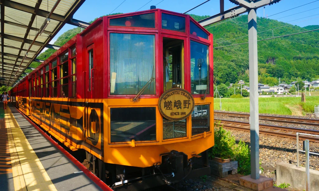 토롯코가메오카역에 정차한 붉은색과 노란색 사가노 토롯코열차